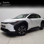 White Toyota compact SUV in a showroom, angled three-quarter front view with black cladding and large alloy wheels, showroom banner reads 'Toyota Ocasión' in the background.
