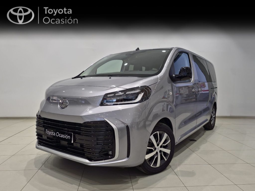 Silver Toyota minivan in a showroom with a 'Toyota Ocasión' banner in the background, front three-quarter view.