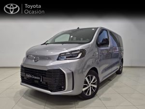 Silver Toyota minivan in a showroom with a 'Toyota Ocasión' banner in the background, front three-quarter view.