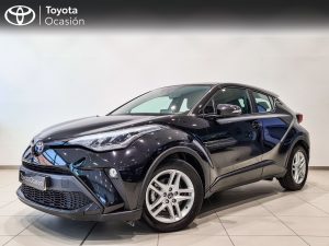 Three-quarter front view of a dark blue Toyota crossover in a showroom, with a 'Toyota Ocasión' banner on the wall.