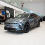 Grey Toyota C-HR on a showroom floor, front three-quarter view showcasing its design and wheels
