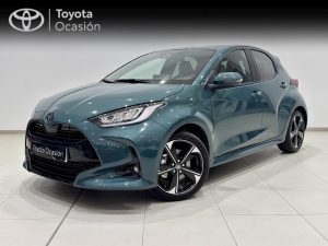 Front three-quarter view of a teal Toyota hatchback in a showroom, with a Toyota Ocasión banner in the background.