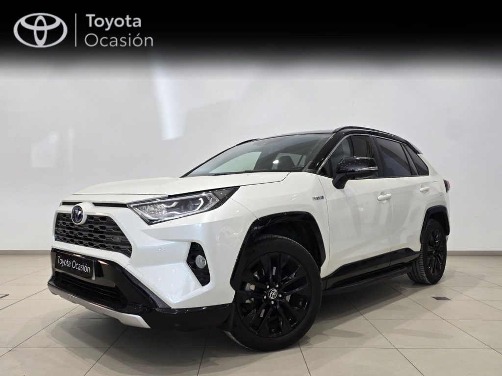 Front three-quarter view of a white Toyota SUV in a showroom, black alloy wheels, Toyota Ocasión banner in the background