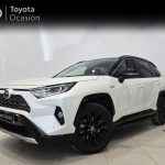 Front three-quarter view of a white Toyota SUV in a showroom, black alloy wheels, Toyota Ocasión banner in the background